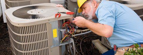 Man in the middle of a heating repair in a yellow hard hat in Orange City